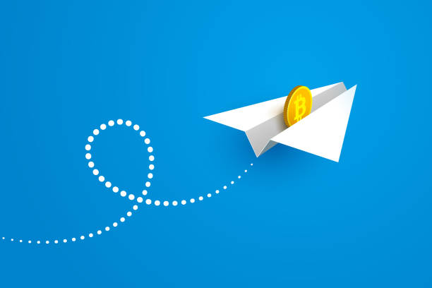 White paper airplane and gold coin with bitcoin sign White paper airplane and gold coin with bitcoin sign over blue background. Concept of money transfers, transactions, online payments, successful business and currency appreciation making money origami stock illustrations