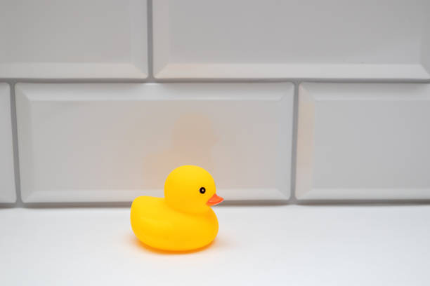 istock Yellow toy duck on a white brick wall in the bathroom 1320004822