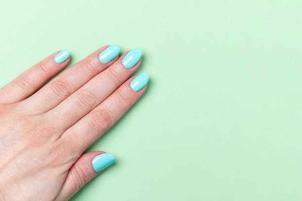 istock Female hand with beautiful manicure - mint blue nails on green background, closeup with copy space 1320004845