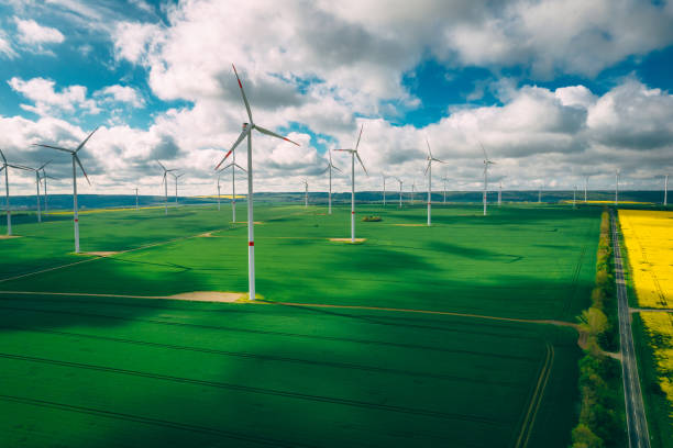 istock wind turbines and agriculture field against clouds 1320005367