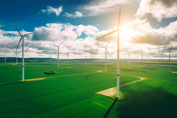 istock wind turbines and agriculture field against clouds 1320005413