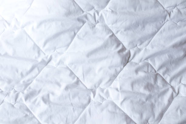 istock White quilted bedspread background. Texture of White Quilted Cover Design duvet. Soft warm blanket 1320006575