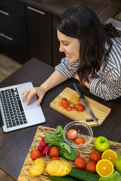 istock woman cooking checking recipe at laptop 1320008115
