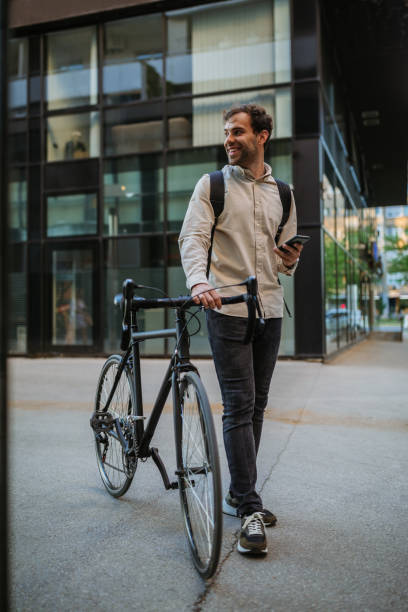 istock Stylish young man standing outside with his bicycle and using phone 1320009740