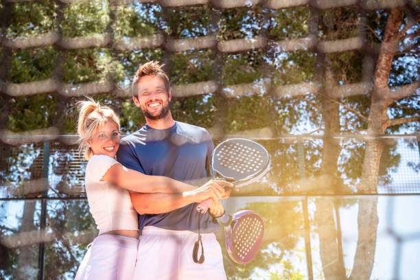 man and a woman happily hug each other after a game of padel in a sunny day stock photo