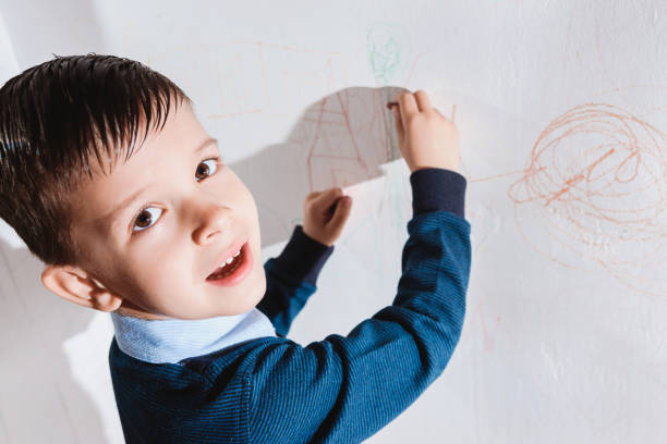 istock Cute child draws on the wall with colored crayons 1320010223