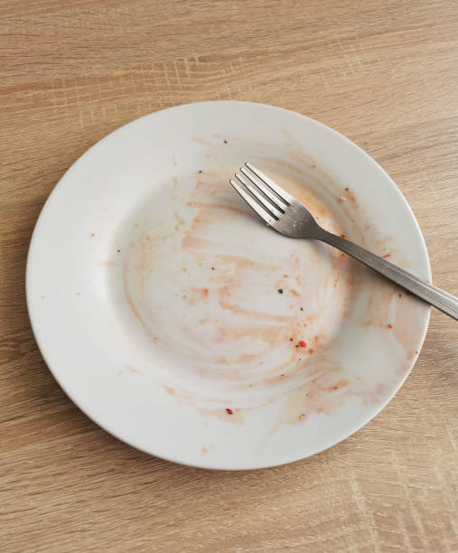 istock Dirty empty plate and fork after dinner on wooden table 1320010341