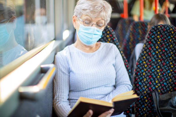 istock Senior woman reading a book in public transportation 1320010963