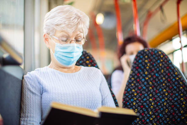 istock Senior woman reading a book in public transportation 1320011079
