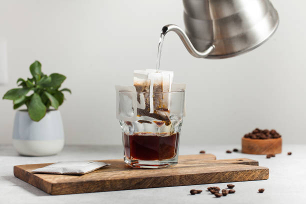 コーヒーを淹れるプロセス。マグカップに滴り落ちるコーヒーバッグに水を注ぎます。自宅でコーヒーを淹れる傾向。 - コーヒー　淹れる ストックフォトと画像