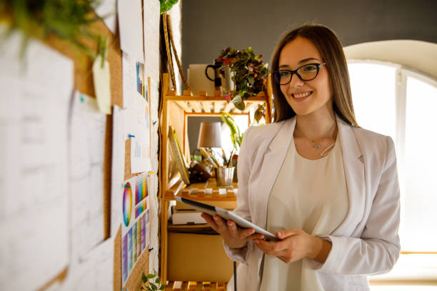 istock Young businesswoman looking at documents on bulletin board and using digital tablet 1320013107