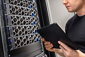 Male IT Support Professional With Digital Tablet Examining Hyper Converged Server Hardware