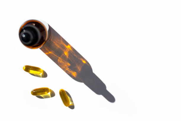 istock Fish oil capsules and bottle with drop shadow on white background. Top view, place for text. 1320020558