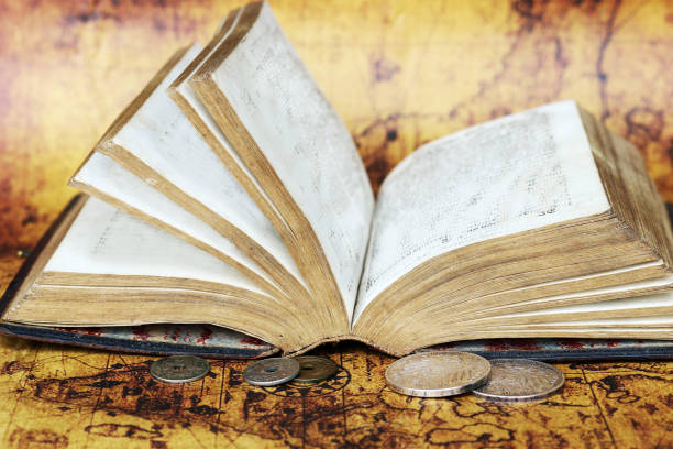 istock Old silver coins from 1902 and an antique book from 1763 on a world map 1320021354