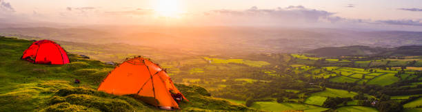 istock Brightly colored dome tents on mountain overlooking sunset landscape panorama 1320021942