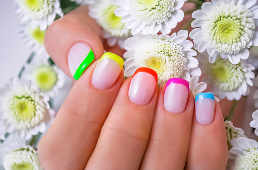 La mano de una joven con una manicura francesa y un diseño arco iris. photo