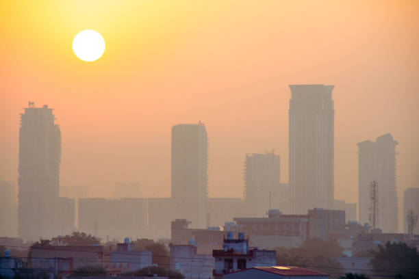 soleil se levant au-dessus des gratte-ciel brumeux brumeux avec les bâtiments grands de plusieurs étages avec de plus petites maisons au premier plan dans la ville de bangalore hyderabad gurgaon et d’autres villes indiennes - bangalore india business building exterior photos et images de collection