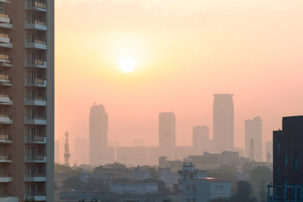 scatto all'alba di grattacielo e piccole case sullo sfondo con edifici alti con uffici di case nascosti dalla nebbia sullo sfondo con il sole che sorge dietro di loro - bangalore india business building exterior foto e immagini stock