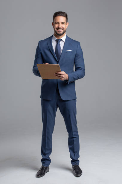 Happy young confident manager with clipboard Happy young confident Caucasian manager with clipboard on gray background necktie fashion adjusting suit stock pictures, royalty-free photos & images