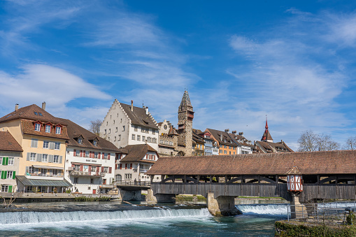 The medieval wooden bridge over Reuss river in Bremgarten is very known and was build 1281. Rebuild 1953. In background the house of administration of abbey Muri-Amthof with the prominent tower.