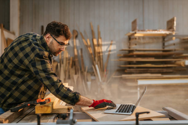 istock Young adult carpenter in workshop using laptop 1320039216