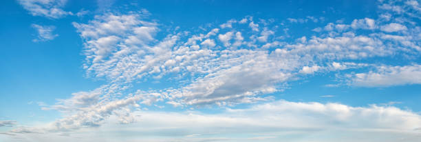 istock Fluffy cirrus clouds float slowly high in the azure blue sky on a sunny day. Panoramic skyscape of many small white clouds are scenic scattered across the sky. Weather and meteorology. Wide banner 1320043558