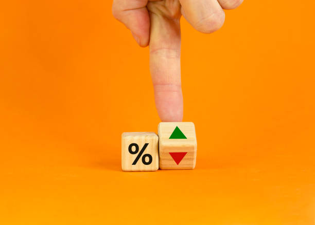 istock Businessman turns a cube, changes the direction of an arrow symbolizing that the interest rates are going down or vice versa. Beautiful orange background. Business, interest rates concept. Copy space. 1320043613
