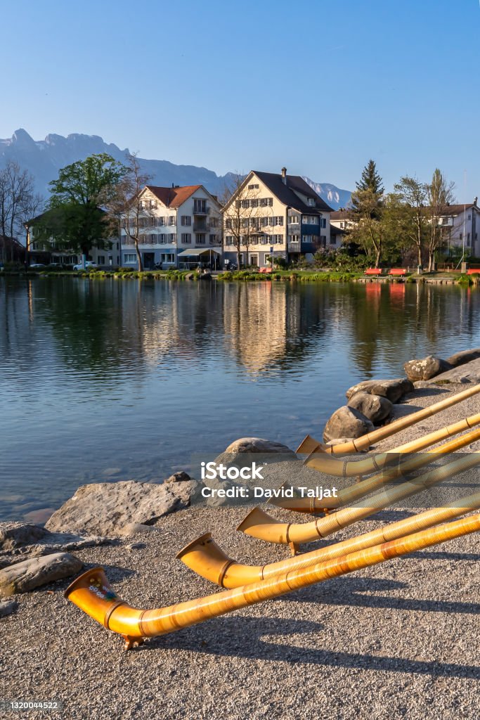 The alpine horns ensemble at the swiss lake and village of Werdenberg The musical instrument alphorn or alpenhorn or alpine horn is a labrophone, consisting of a straight several meter long wooden natural horn of conical bore, with a wooden cup shaped mouthpiece. Lake Stock Photo