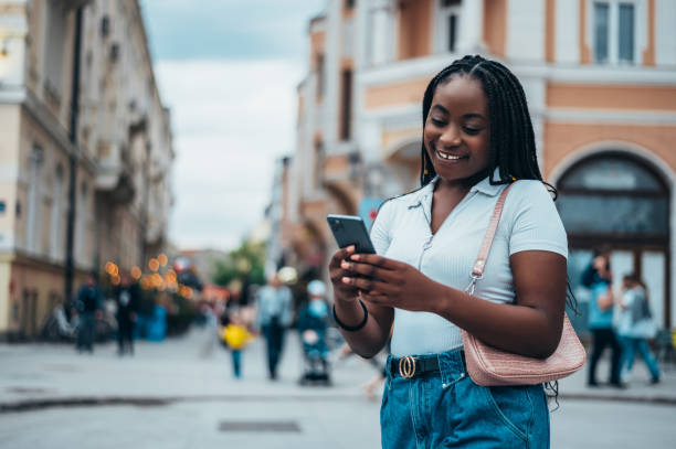istock Cheerful african american woman using smartphone outside 1320044680