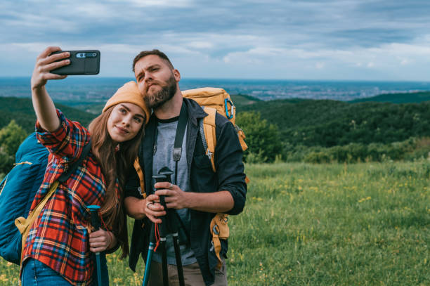 istock Hikers taking selfie with a smartphone and using trekking poles while wearing backpacks 1320044690
