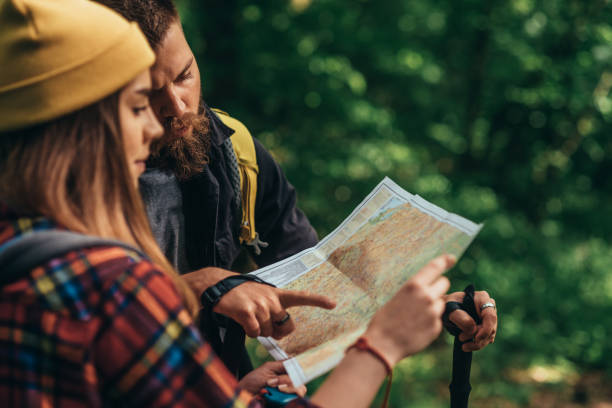 istock Couple of hikers using trekking poles and map while wearing backpacks 1320044700