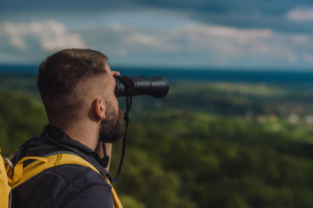 a hiker man using binoculars for orientation in the nature - footpath field nature contemplation imagens e fotografias de stock