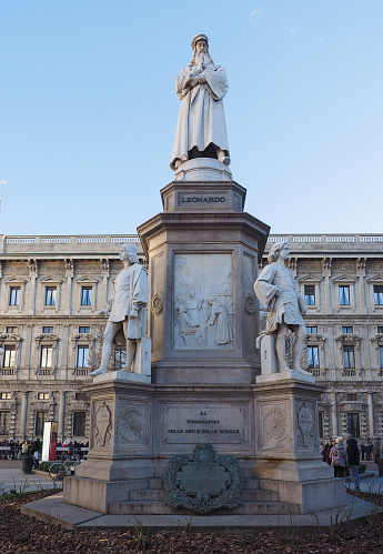 Statue of Hungarian  Sándor Petőfi. The statue is gray and standing on a foundation. The background is green trees  and a clear blue sky in the upper right corner. The statue stands on Petőfi Square downtown Budapest. It was made by Miklós Izsó and Adolf Huszár in 1882.