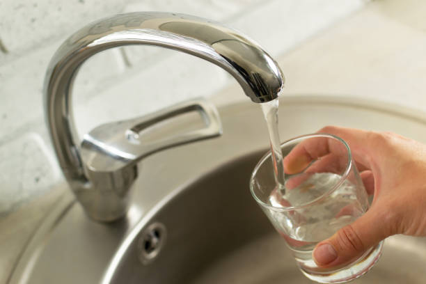 istock A hand with a glass draws water from the kitchen tap. 1320049726