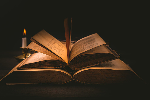 Old antique books with candle in vintage style on wooden black background