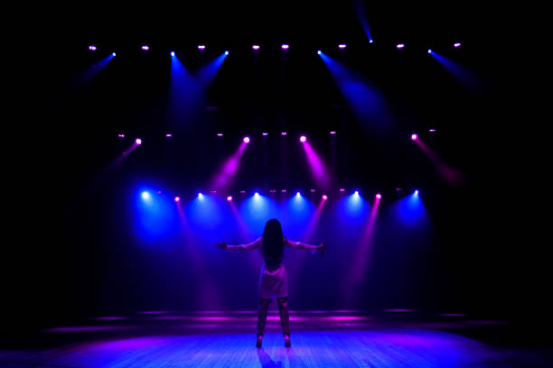 istock Unrecognizable singer standing on stage at microphone, back view, neon lights 1320049803