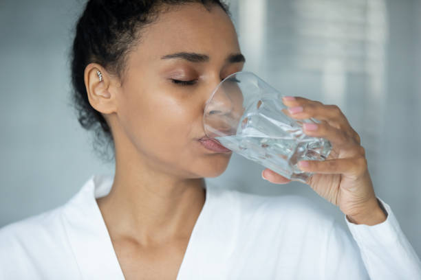 istock Peaceful mixed race woman in bathrobe drinking good quality water 1320049986