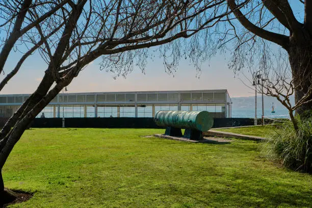 Photo of Old and ancient gun on green grass and exhibited for tourist visited to dolmabahce palace with bosporus background during sunny day.