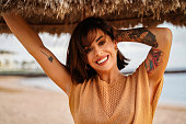 Beautiful smiling woman portrait in sunset on the beach. Girl with tattoos.