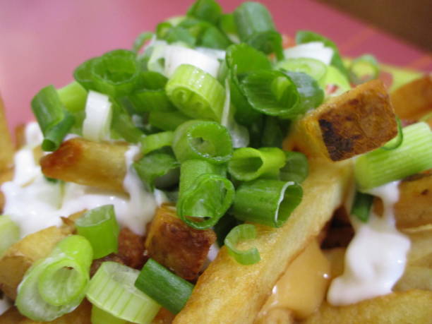 istock Bright Delicious Poutine Topped with Green Onions and Cheese Sauce 1320050987