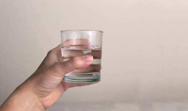 istock A woman's hand holds a glass glass with clean water. 1320051024