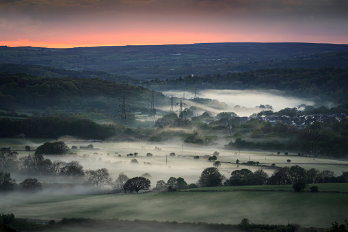 Misty valley in Leeds, Yorkshire with electricity pylons.