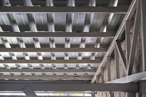 Bottom side of a metal roof and construction frame made of profile metals and white color.