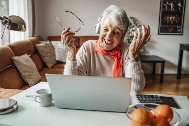 istock Senior woman sitting at the table at home and using laptop 1320052050
