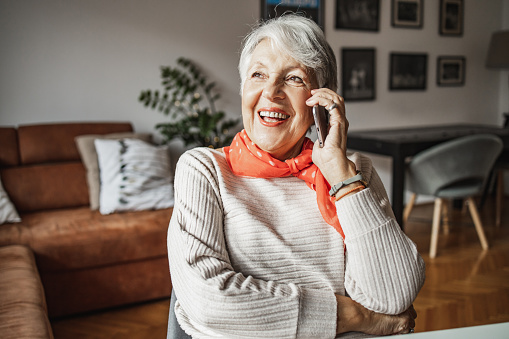 Photo of a happy senior woman smiling while talking on the phone