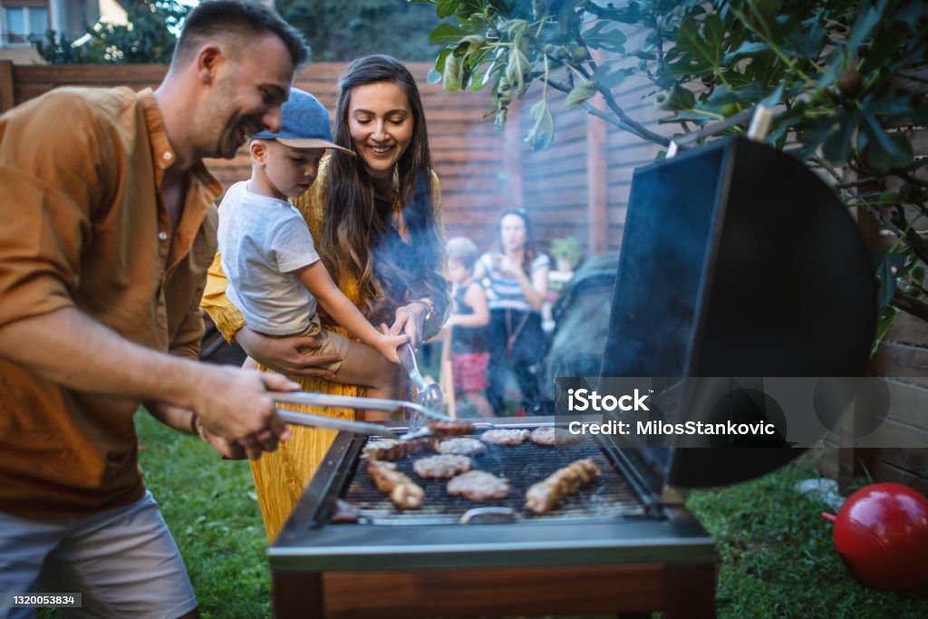 Barbecue party in backyard Photo of young happy family having a barbecue party in backyard Barbecue Grill Stock Photo