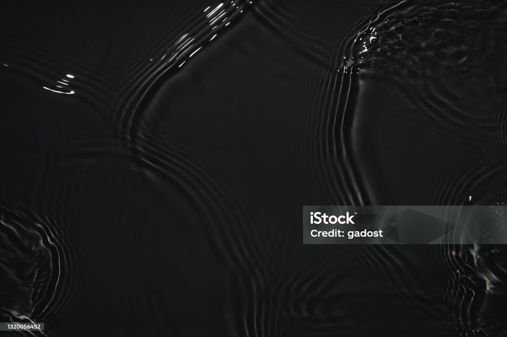 black transparent clear calm water surface texture Black transparent clear calm water surface texture with ripples, splashes Abstract nature background. Dark grey water waves in sunlight Copy space Cosmetic moisturizer micellar toner emulsion Liquid Stock Photo