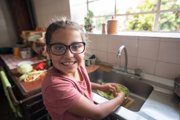 chica latinoamericana ayudando en la cocina y luciendo muy feliz - farmer salad fotografías e imágenes de stock