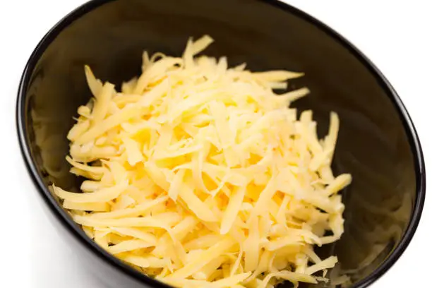 Grated cheddar cheese in a black bowl.