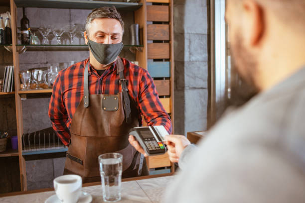 istock Waiter wearing a facemask while getting a contactless payment at a restaurant 1320062558